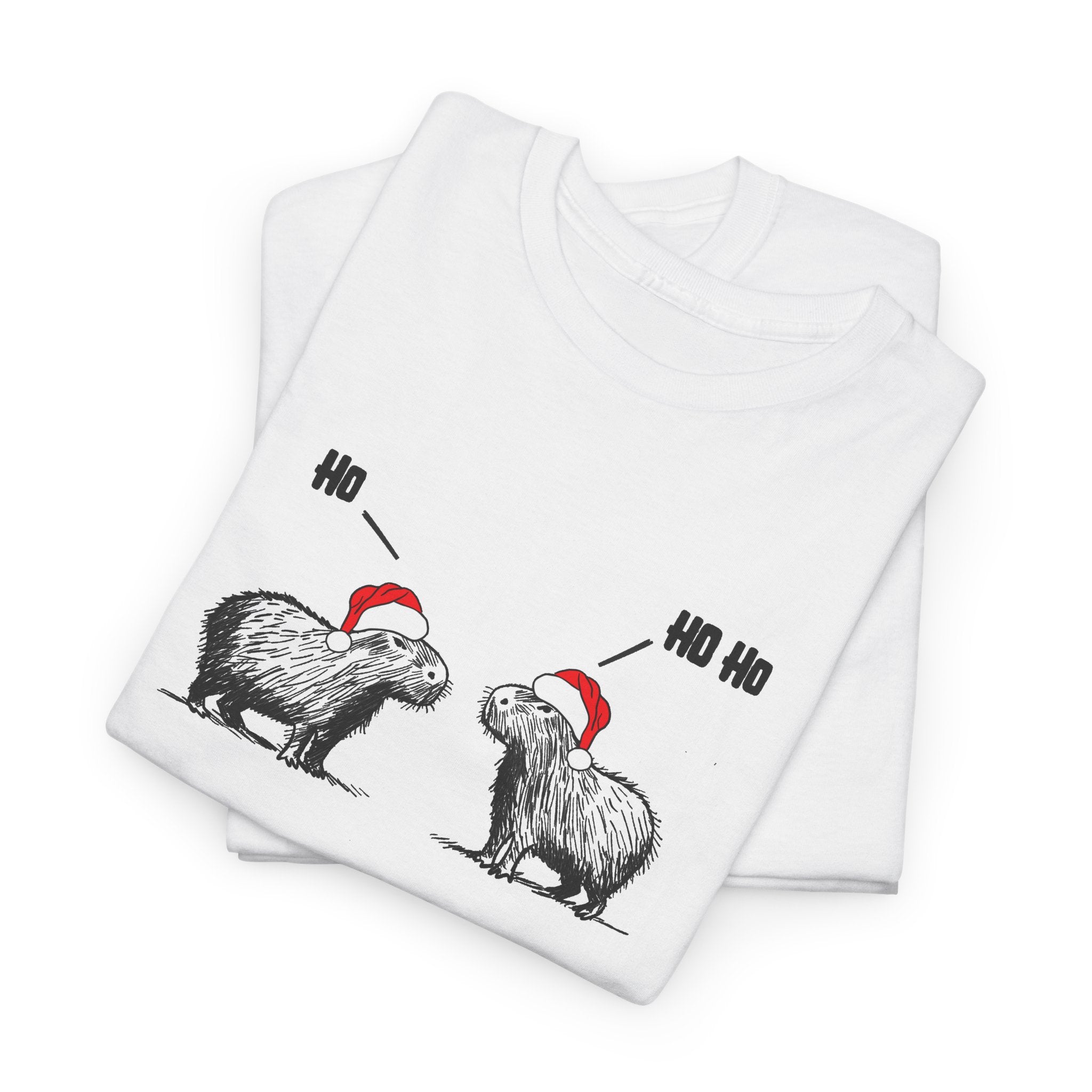 A folded white short-sleeve crewneck t-shirt featuring a graphic of two fluffy capybara wearing red Santa hats, with 'Ho Ho Ho' text above them,