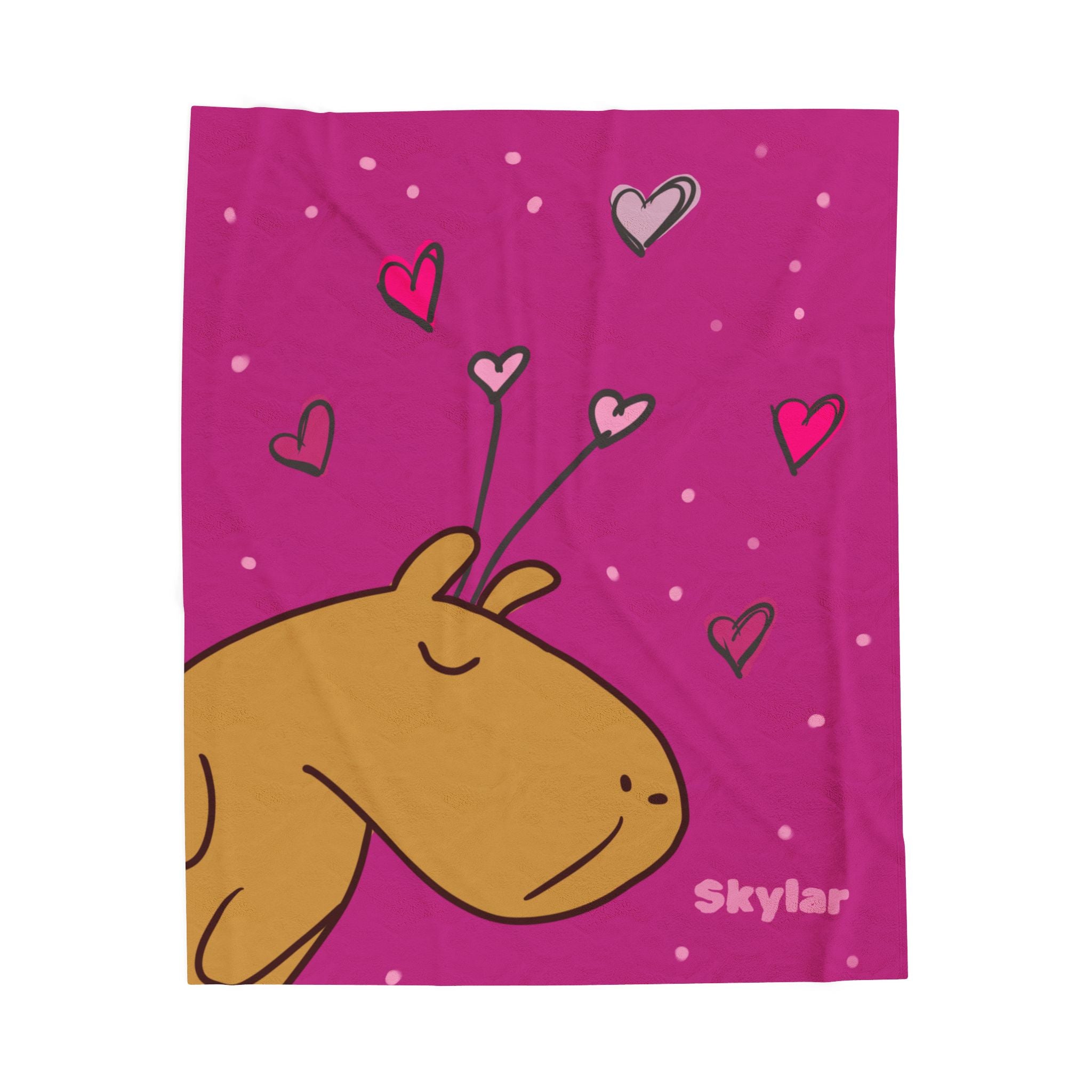 Personalized pink velveteen blanket with cartoon capybara and heart shapes, featuring the brand name Skylar.