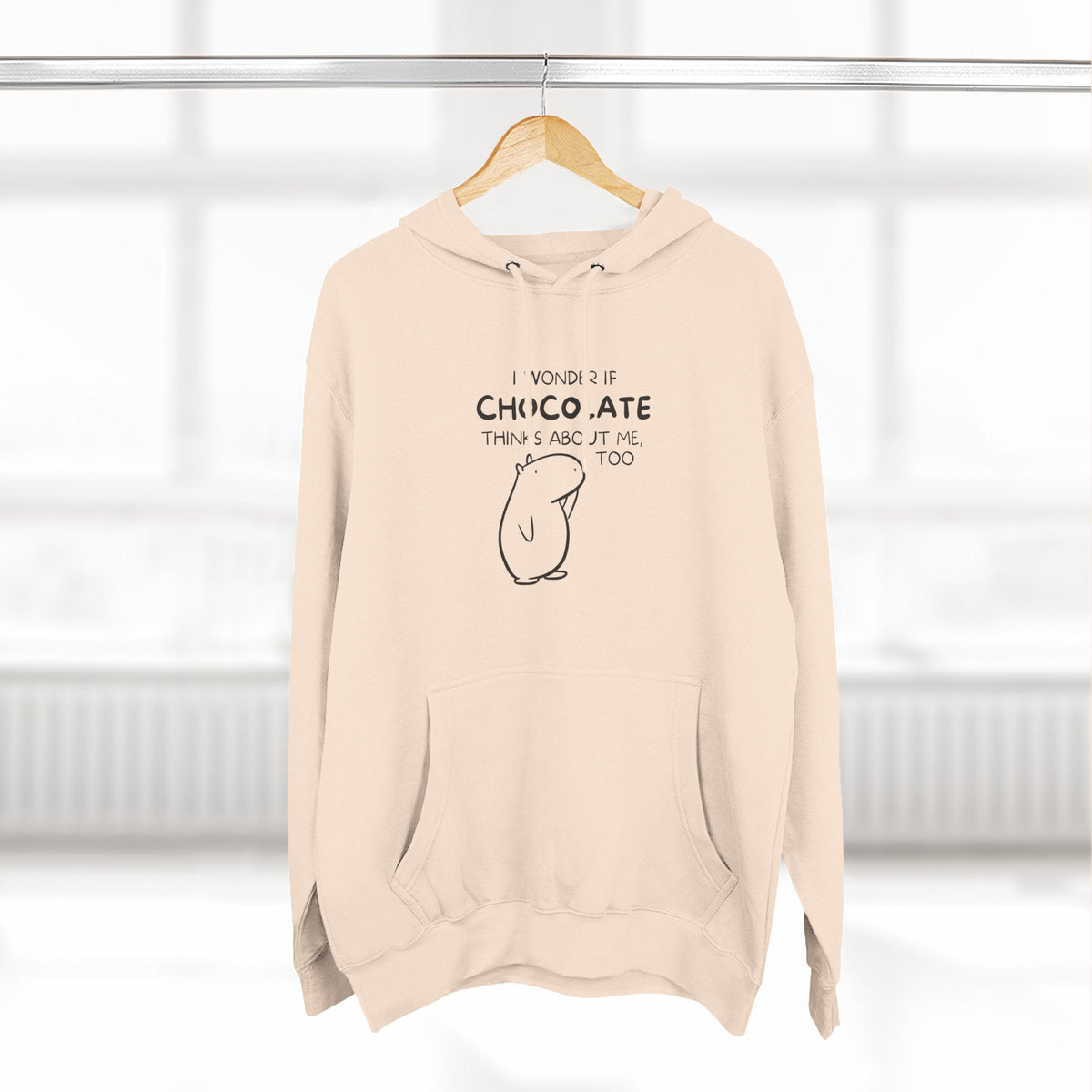 Capy Life premium beige hoodie featuring Gene the Capybara line art and the text I Wonder If Chocolate Thinks About Me Too