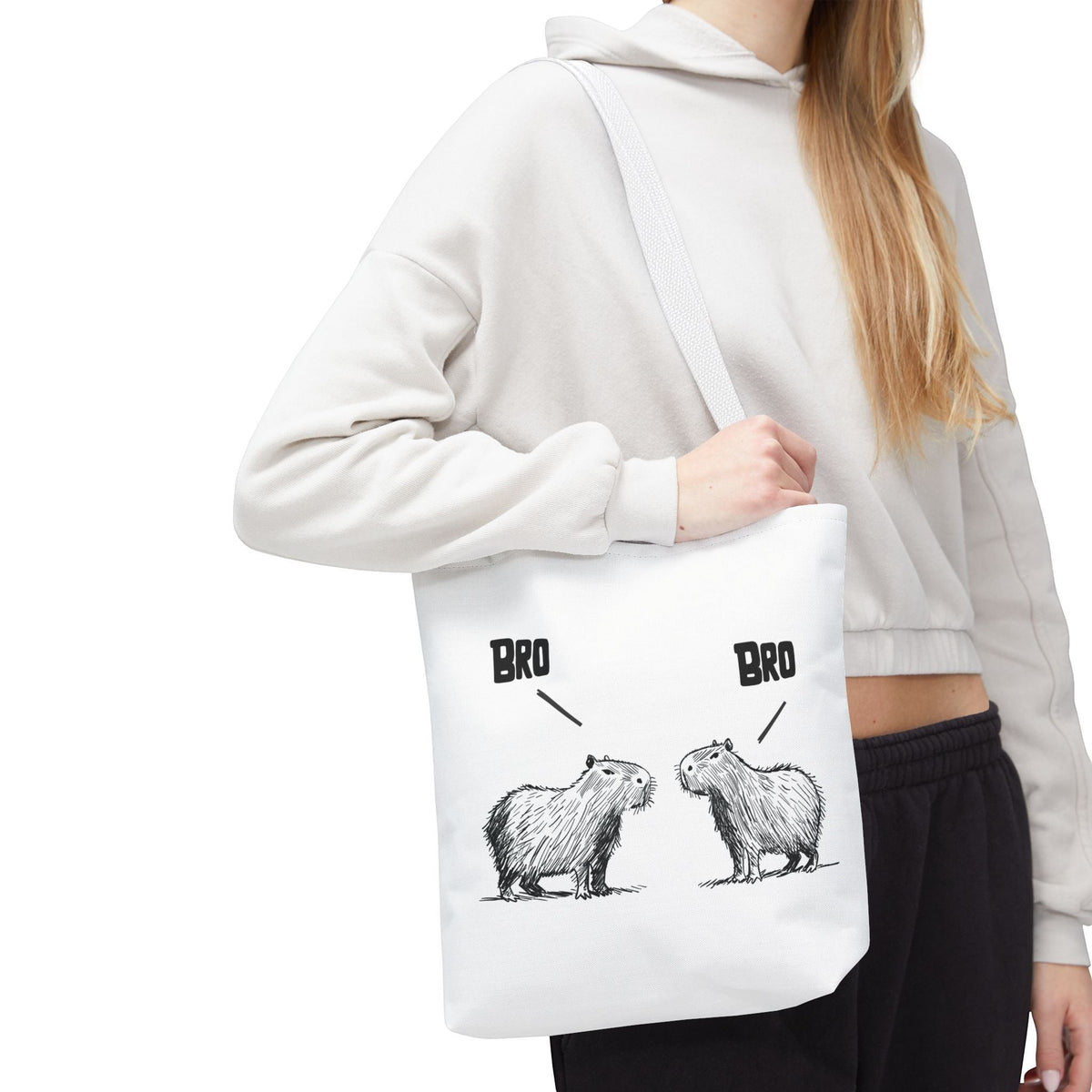 Capy Life white canvas tote bag featuring a funny sketch of two capybaras saying Bro, worn over the shoulder.