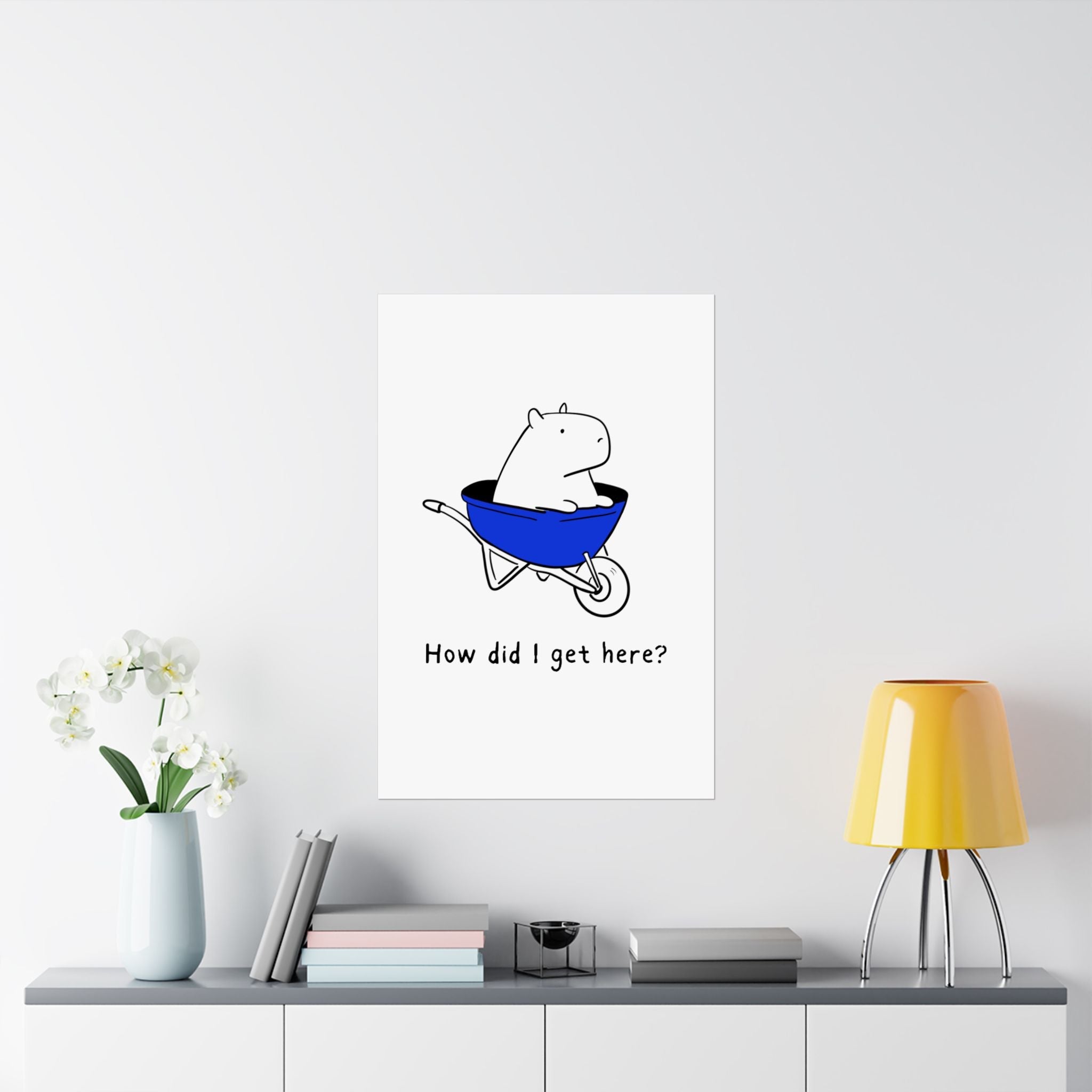 Capy Life minimalist wall art print featuring a capybara in a blue wheelbarrow with the text How did I get here?