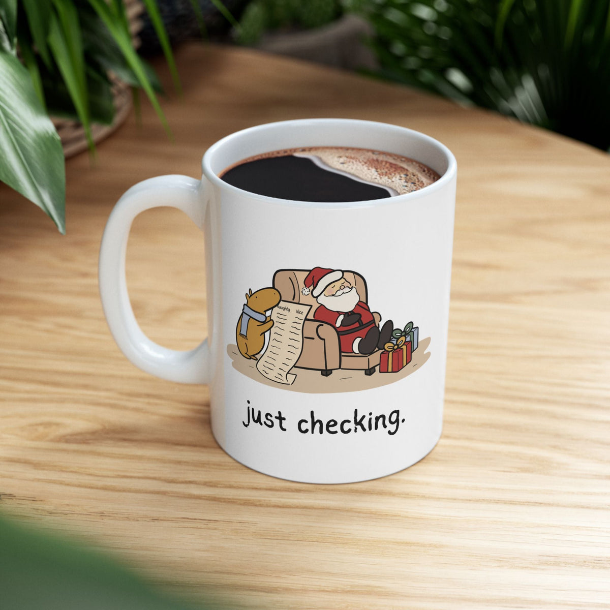 Capy Life white ceramic mug featuring a capybara in a blue scarf checking Santa's naughty or nice list.