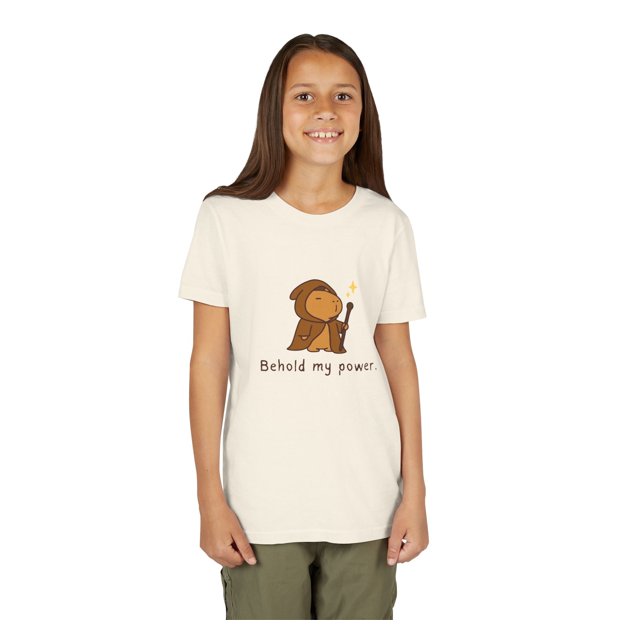 A young girl wearing a Capy Life cream-colored cotton t-shirt featuring a cute capybara wizard graphic and text.