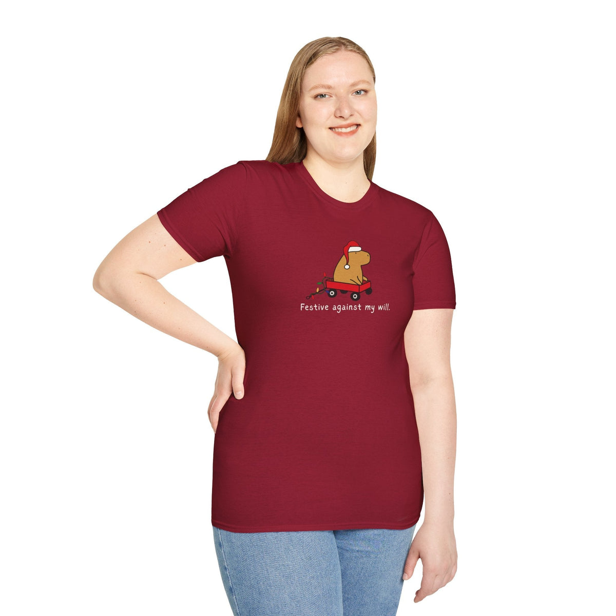 Woman wearing a maroon Capy Life softstyle t-shirt featuring a capybara in a red wagon with the text Festive against my will
