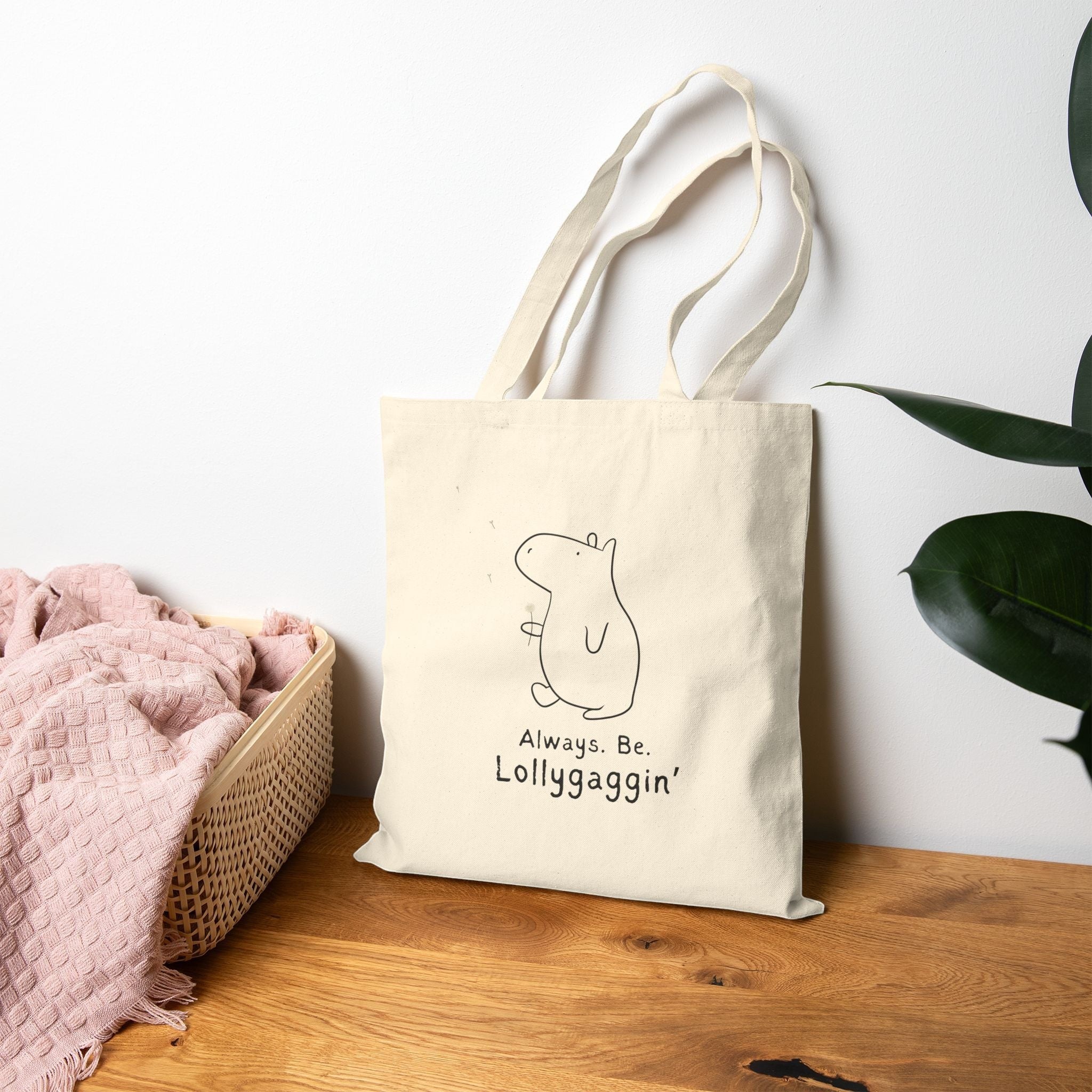 Capy Life natural canvas tote bag featuring a minimalist capybara illustration and the text Always Be Lollygaggin