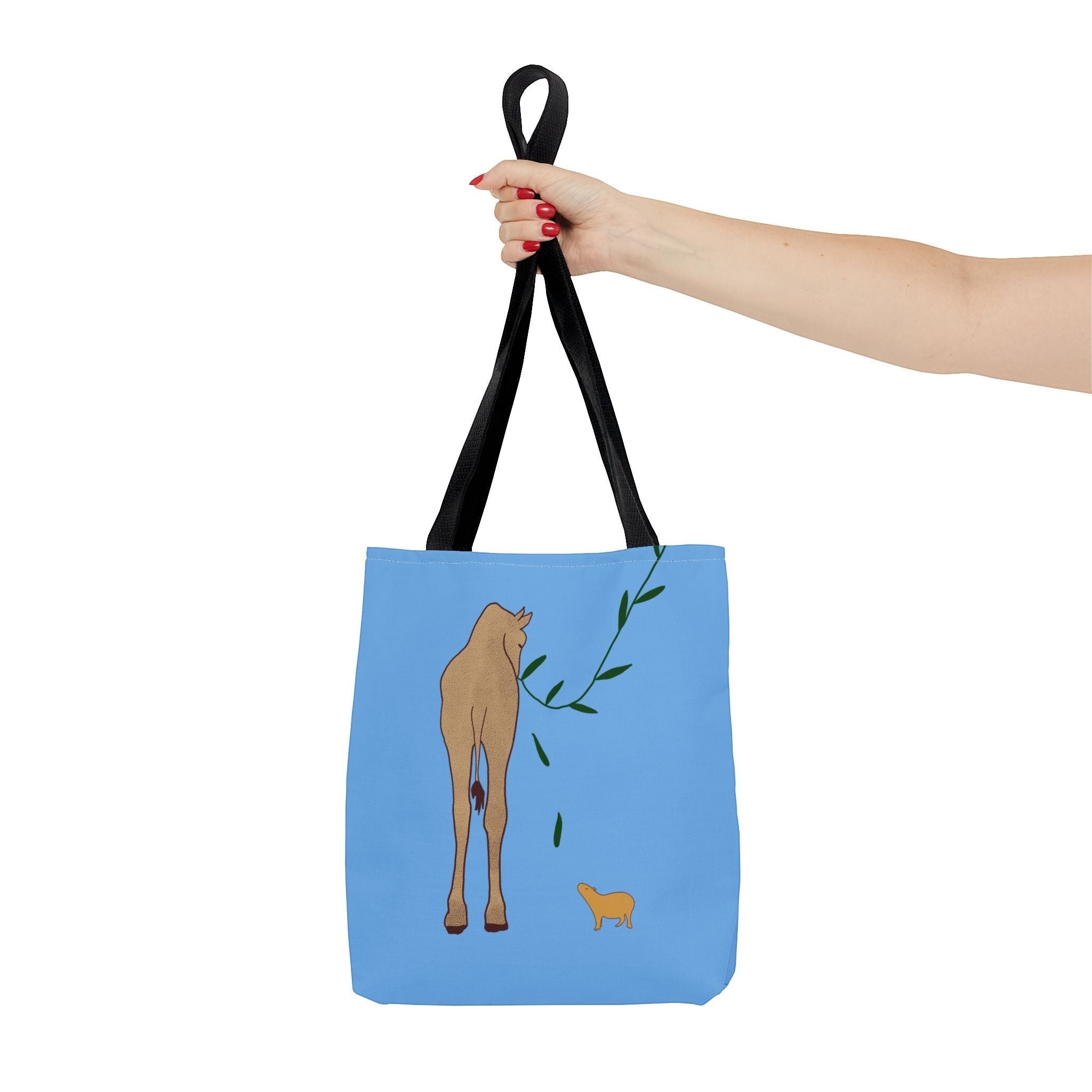 Capy Life minimalist blue tote bag featuring a giraffe and capybara illustration held by a hand.
