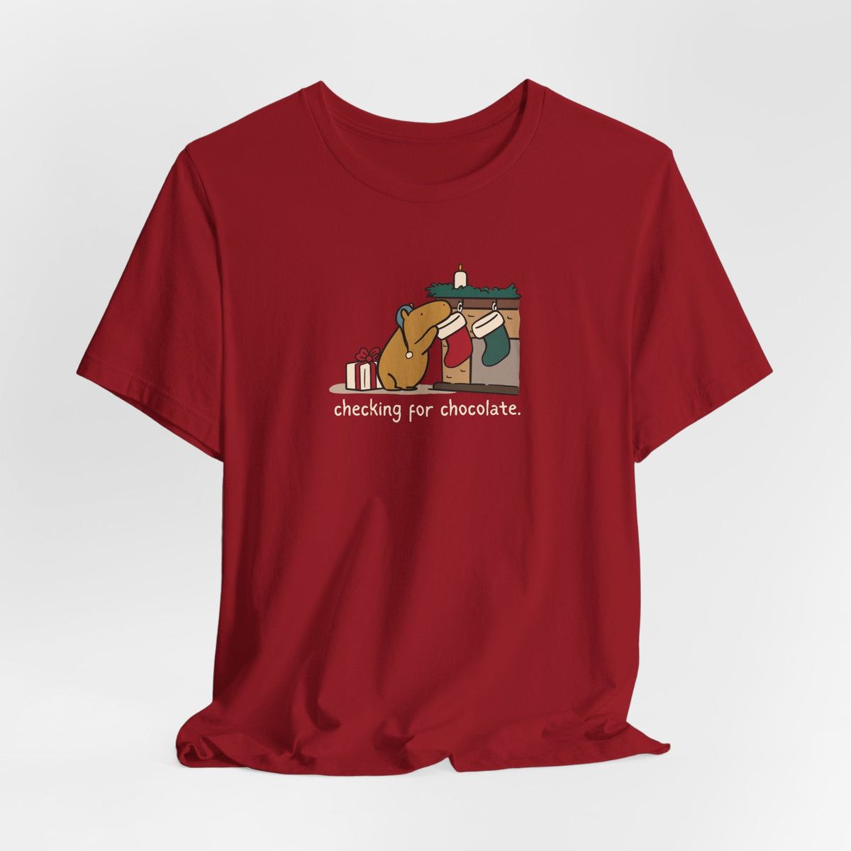 Capy Life red softstyle t-shirt featuring a hand-drawn capybara checking a Christmas stocking for chocolate.