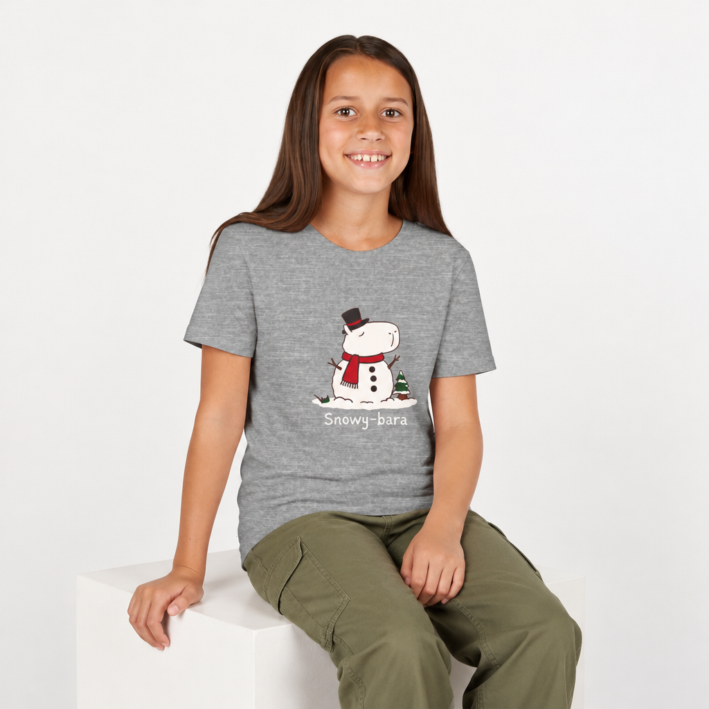 A young girl wearing a Capy Life grey youth t-shirt featuring a cute Snowy-bara snowman capybara graphic.