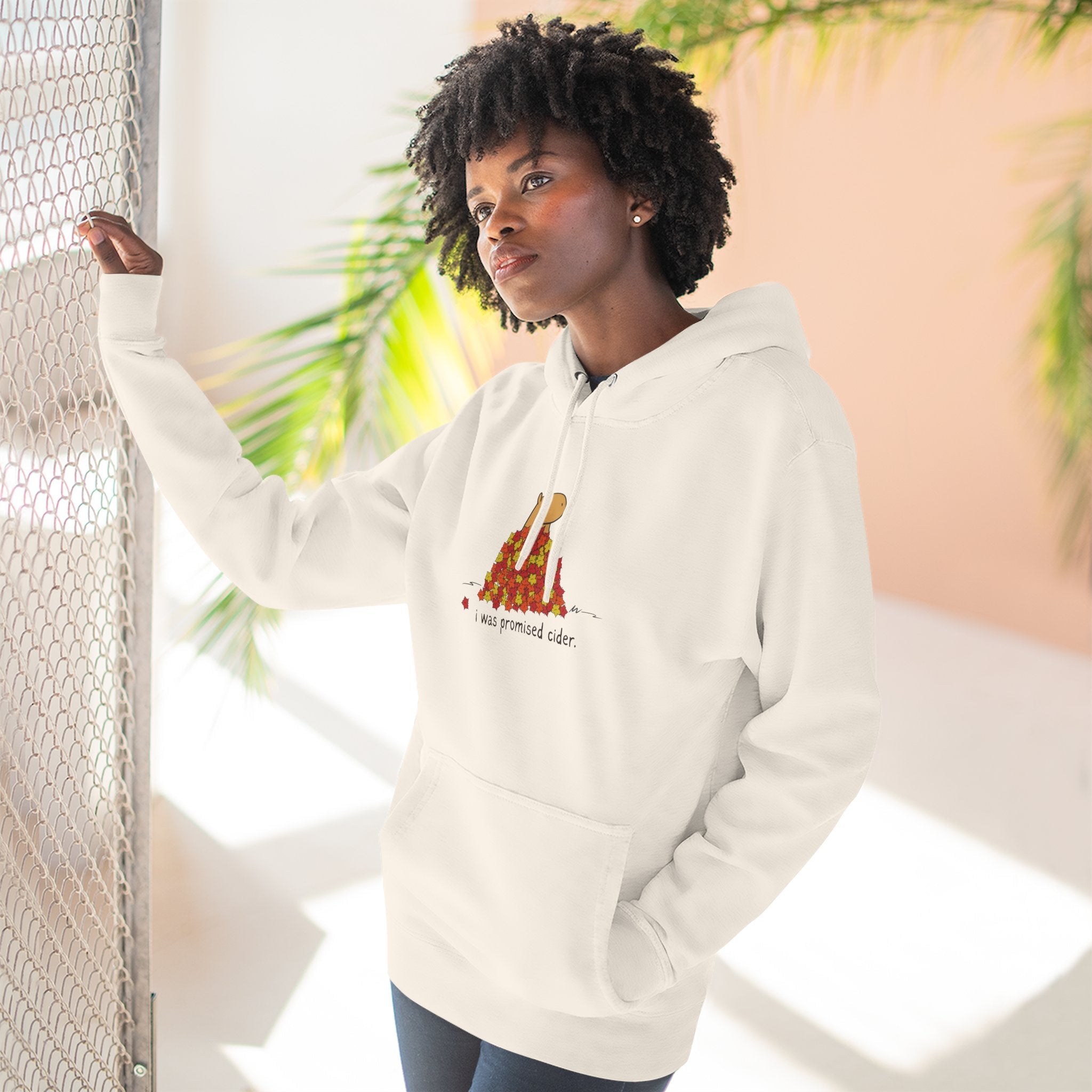 A woman wearing a Capy Life white fleece hoodie with a capybara graphic and the text I was promised cider.