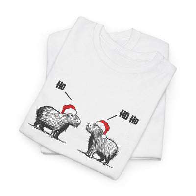 A folded white short-sleeve crewneck t-shirt featuring a graphic of two fluffy capybara wearing red Santa hats, with 'Ho Ho Ho' text above them,