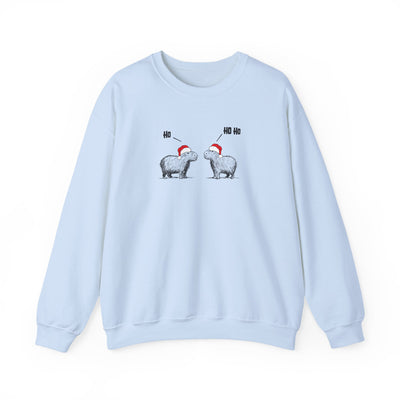 A light blue crewneck sweatshirt featuring a graphic of two capybaras wearing red Santa hats facing each other with 'HO HO HO' text above them, displayed on a clean white background.