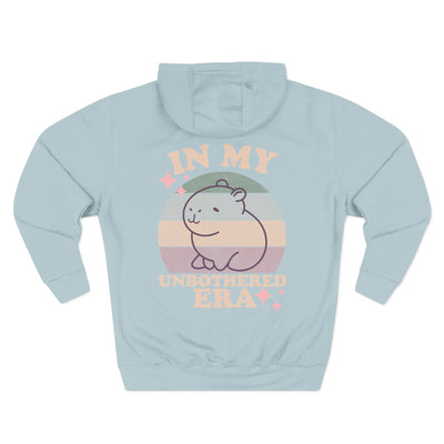 Mint green hoodie with capybara graphic on front and retro sun design on back, text reads "In My Unbothered Era