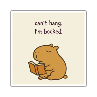 Cozy cartoon capybara reading a book, with text "can't hang, I'm booked" on beige background