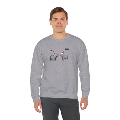 A man wearing a heather gray crewneck sweatshirt featuring a graphic of two capybaras wearing red Santa hats facing each other with 'HO HO HO' text above them