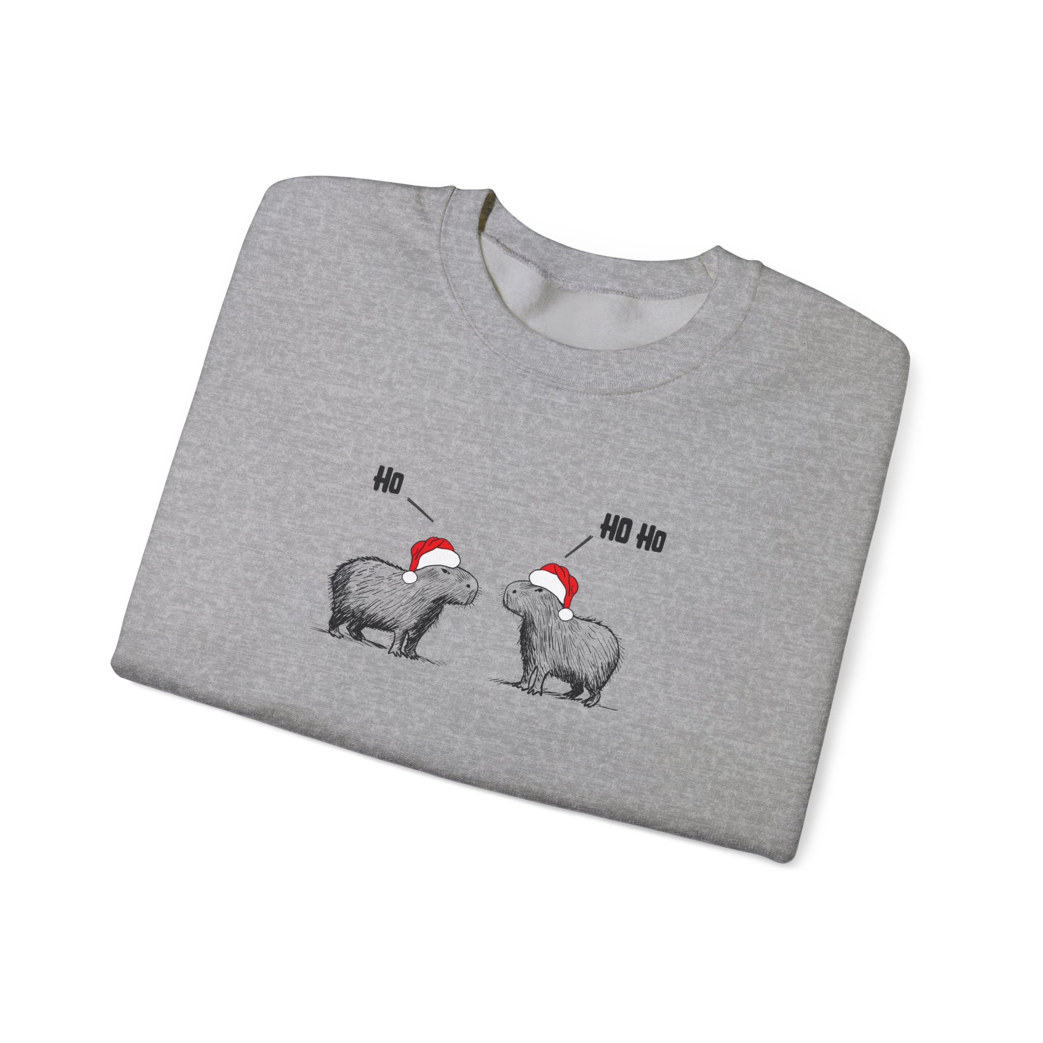 Folded gray crewneck sweatshirt featuring a graphic of two capybaras wearing red Santa hats facing each other with 'HO HO HO' text above them