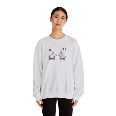 Person wearing a gray crewneck sweatshirt featuring a graphic of two capybaras wearing red Santa hats facing each other with 'HO HO HO' text above them