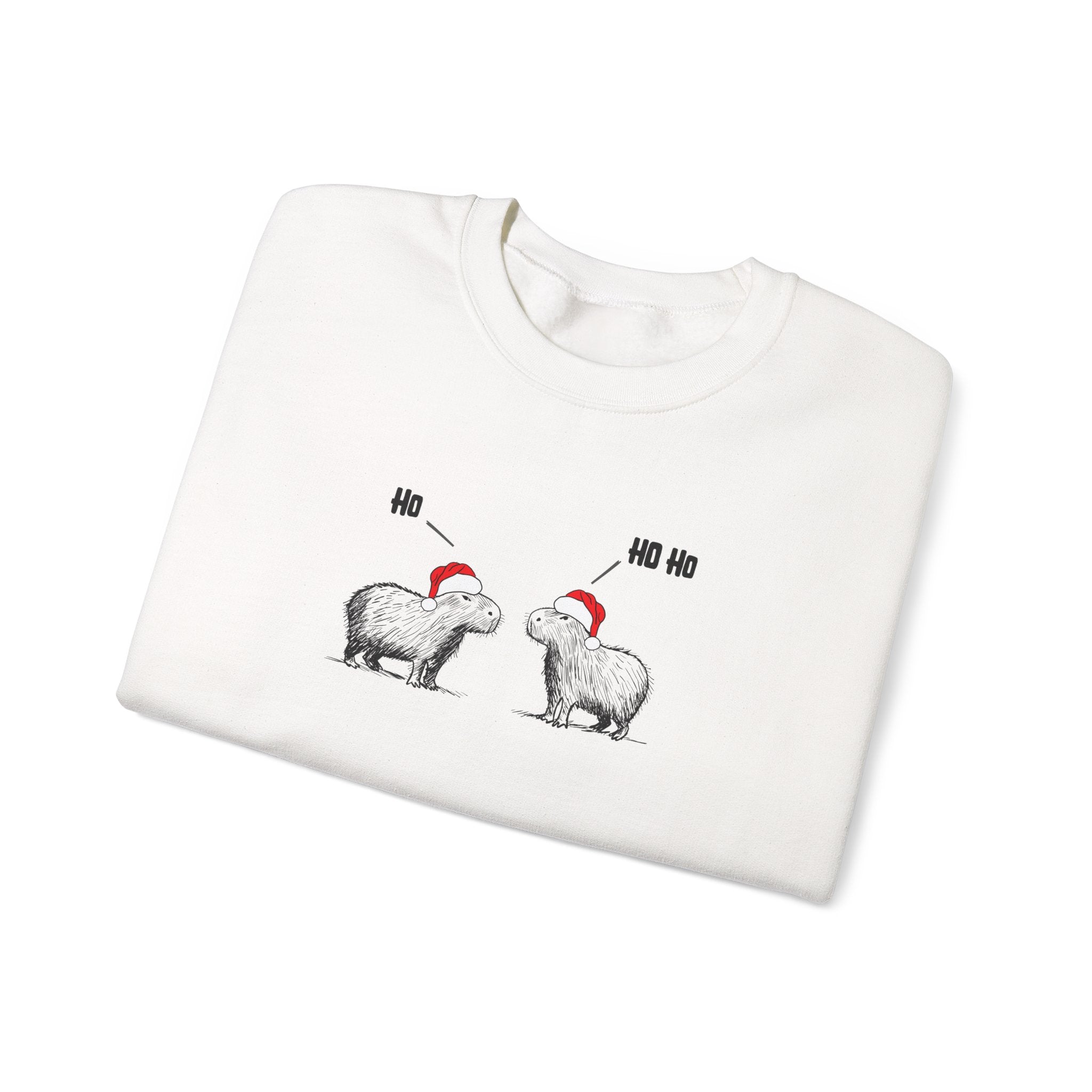 A folded white crewneck sweatshirt featuring a graphic of two capybara animals wearing red Santa hats, with one labeled 'Ho' and the other 'Ho Ho', on a plain white background.