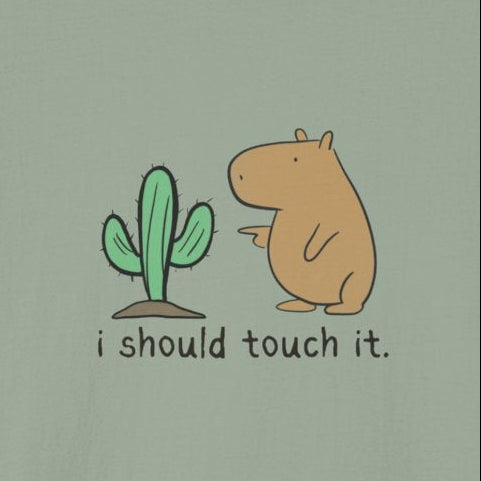 short-sleeve crewneck t-shirt featuring a cute graphic of a small green cactus and a brown capybara with the text 'i should touch it.' printed on the chest, displayed against a solid white background.