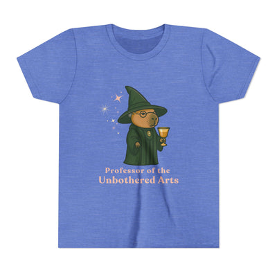 Whimsical youth t-shirt featuring a capybara wearing a green wizard's hat holding a golden cup against a starry blue background, text reads "Professor of the Unbothered Arts