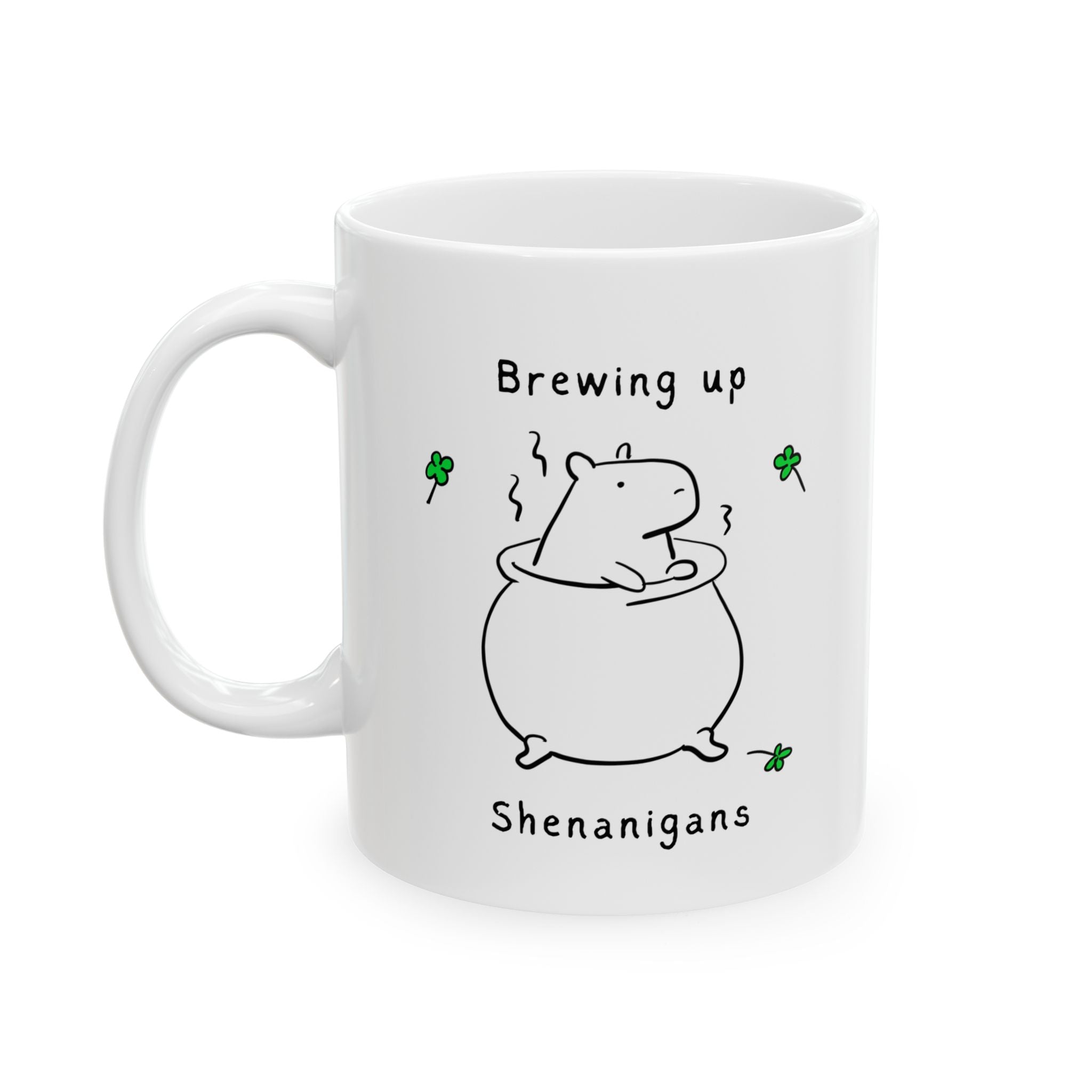 White ceramic mug with illustration of a capybara and text "Brewing up Shenanigans" and shamrocks, St. Patrick's Day coffee cup