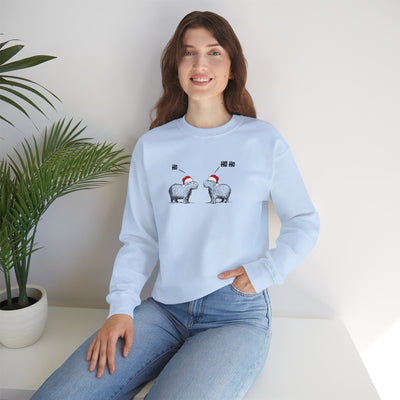 Woman wearing a light blue crewneck sweatshirt featuring a graphic of two capybaras wearing red Santa hats facing each other with 'HO HO HO' text above them