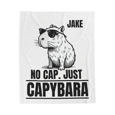 Black and white illustration of a capybara wearing sunglasses, with text "JAKE NO CAP JUST CAPYBARA" on a white fleece blanket.