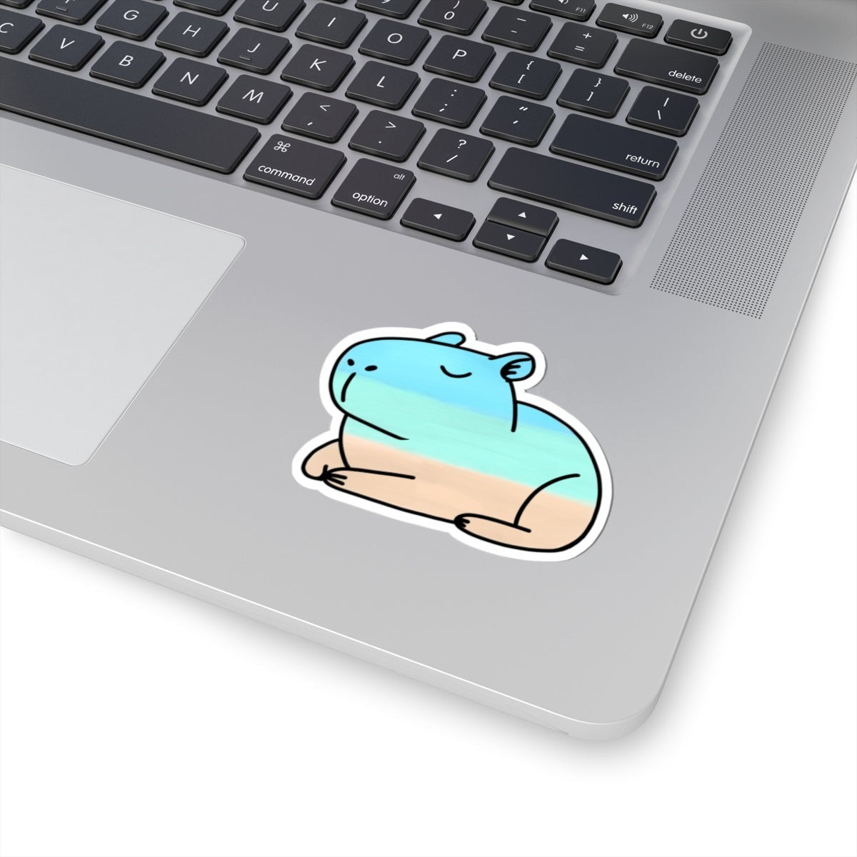 Capy Life beach capybara sticker with watercolor blue, turquoise, and sandy beige layers on a laptop surface