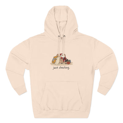 Capy Life beige fleece hoodie featuring a hand-drawn capybara checking Santa's naughty-or-nice list.