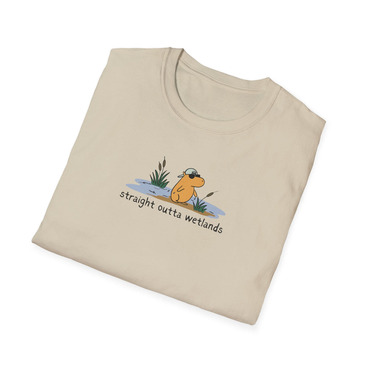 Capy Life beige softstyle t-shirt featuring a hand-drawn capybara wearing a backwards hat in a wetland scene.