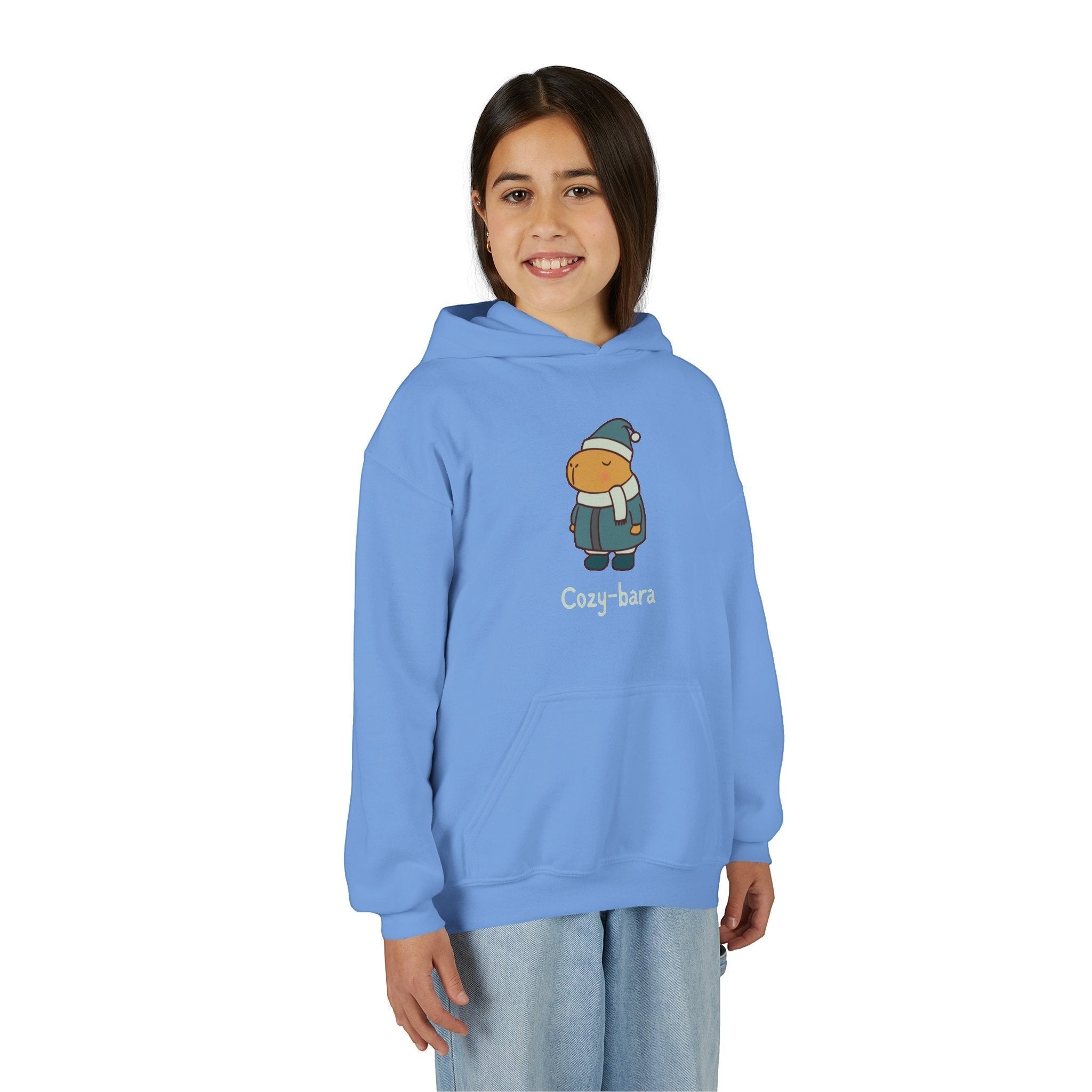 A young girl wearing a light blue Capy Life Cozy-bara hoodie featuring a cute capybara graphic in winter gear.