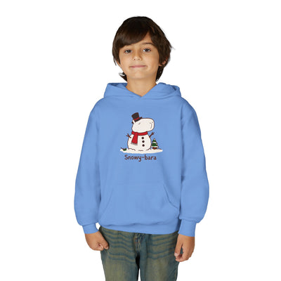 A young boy wearing a light blue Capy Life pullover hoodie featuring a cute Snowy-bara capybara snowman graphic.