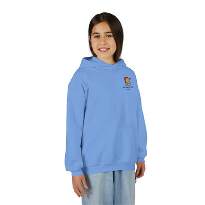 A young girl wearing a light blue Capy Life kids hoodie featuring a patriotic capybara graphic and kangaroo pocket.