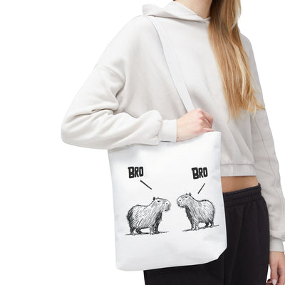 Capy Life white canvas tote bag featuring a funny sketch of two capybaras saying Bro, worn over the shoulder.