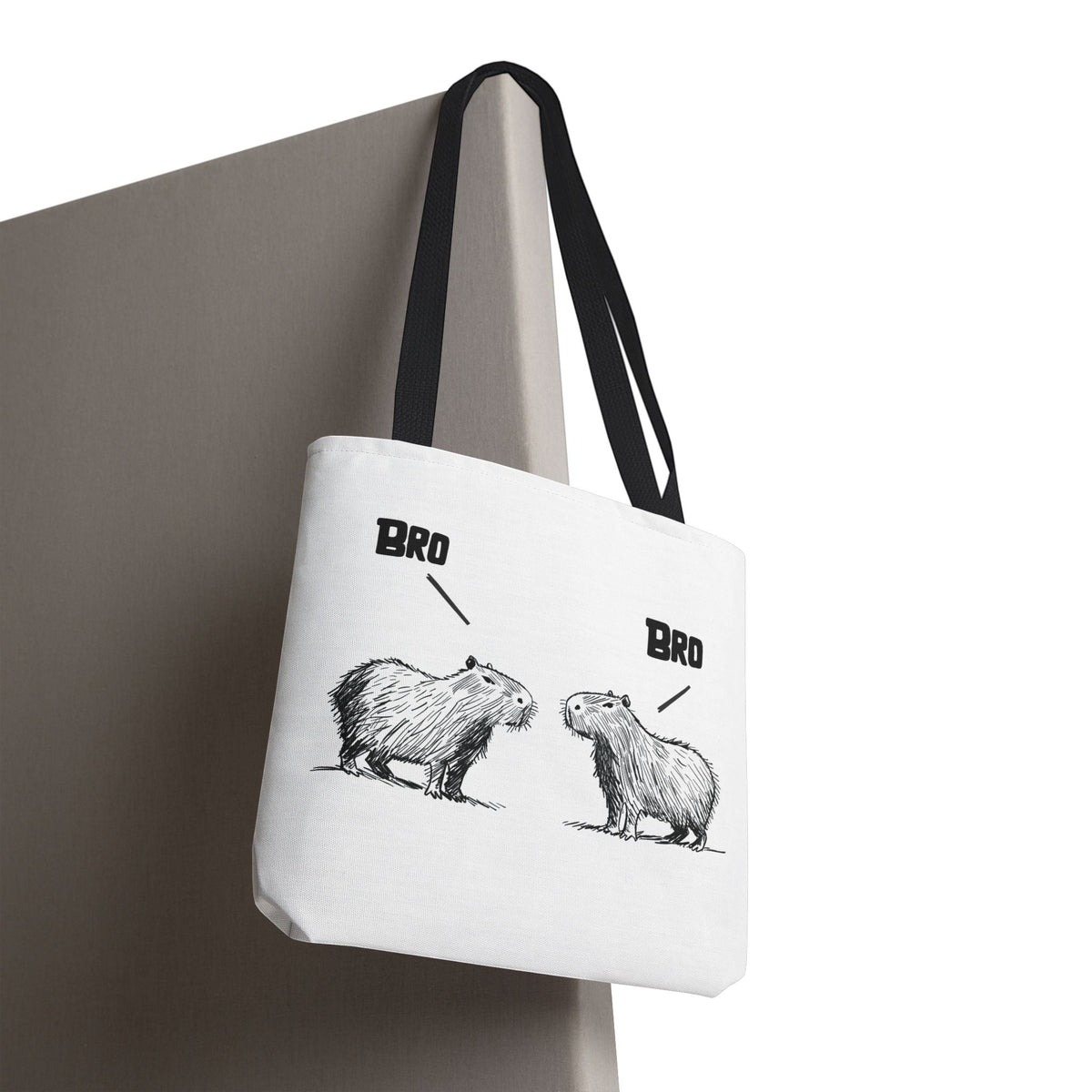Capy Life white canvas tote bag featuring a minimalist sketch of two capybaras saying Bro to each other with black handles