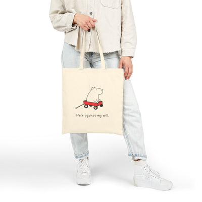 Capy Life natural canvas tote bag featuring a funny capybara in a red wagon with the text Here against my will.