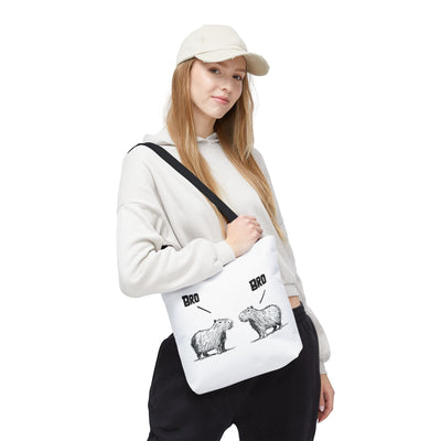 Capy Life premium white canvas tote bag with funny capybara line art, worn by a woman in a beige hoodie and cap.