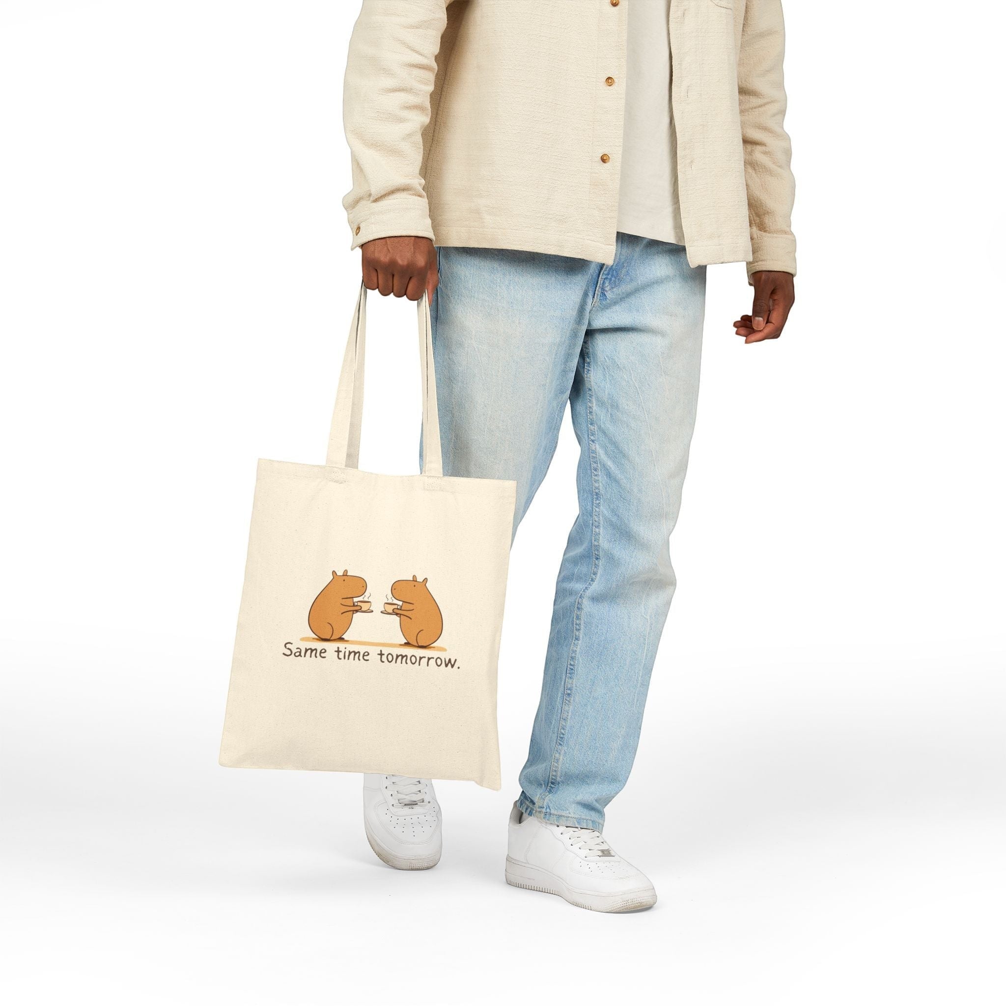Capy Life canvas tote bag featuring two hand-drawn capybaras with coffee, held by a person in casual clothing.