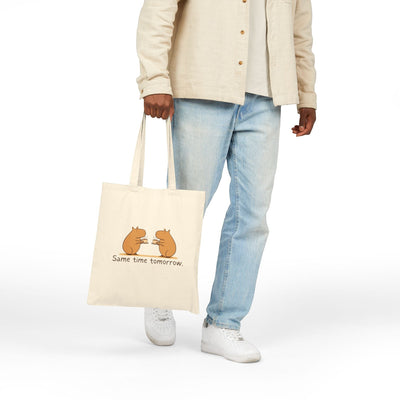 Capy Life canvas tote bag featuring two hand-drawn capybaras with coffee, held by a person in casual clothing.