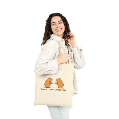 A woman wearing a corduroy jacket carries a Capy Life natural canvas tote with a capybara coffee illustration.