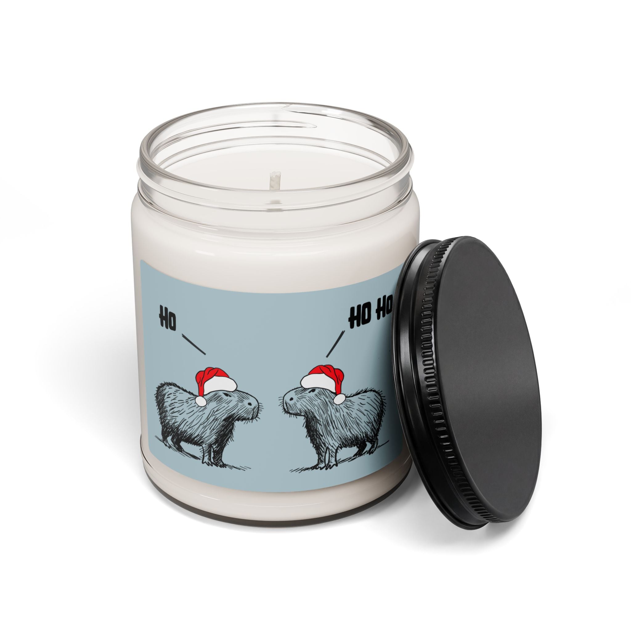 Capy Life Christmas candle featuring two capybaras in Santa hats on a blue label with Ho Ho text and black lid.