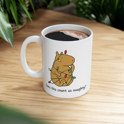 Capy Life white ceramic mug featuring a capybara tangled in colorful Christmas lights with the text Does this count as naughty?