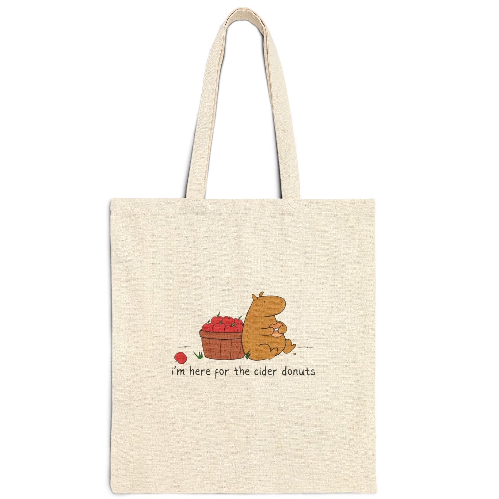 Capy Life natural canvas tote bag featuring a cute capybara eating a cider donut next to a basket of red apples.
