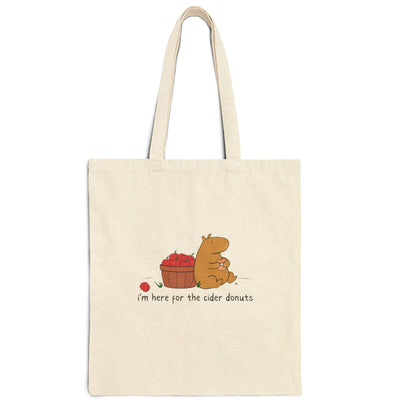 Capy Life natural canvas tote bag featuring a cute capybara eating a cider donut next to a basket of red apples.