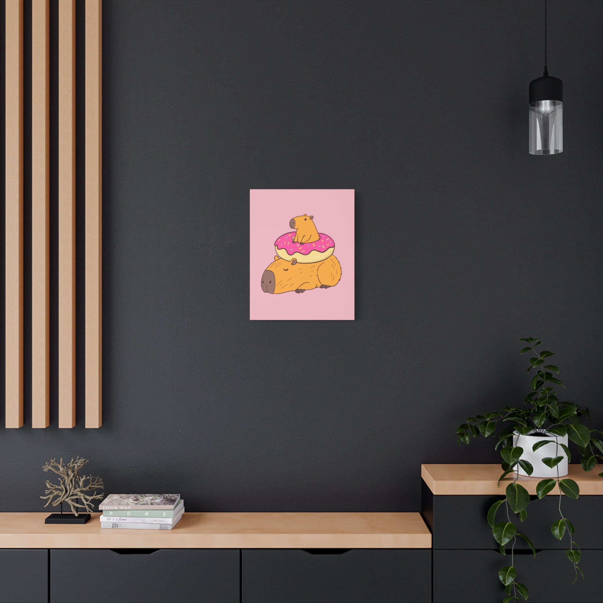 Capy Life canvas wall art featuring a cute capybara resting with a baby capybara in a pink donut on a dark wall.
