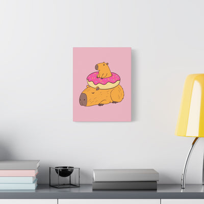 Capy Life canvas wall art featuring a relaxed capybara with a smaller one sitting in a pink donut on a soft pink background.