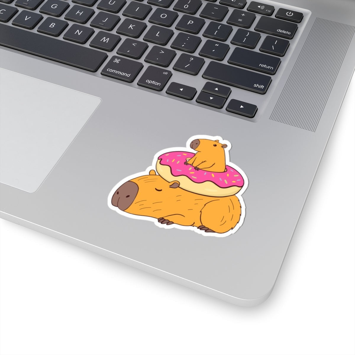 Capy Life sticker featuring two cute capybaras, one napping and one sitting inside a pink frosted donut on a laptop.