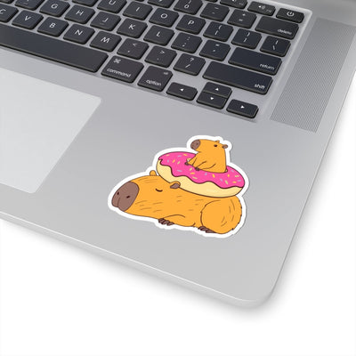 Capy Life sticker featuring two cute capybaras, one napping and one sitting inside a pink frosted donut on a laptop.