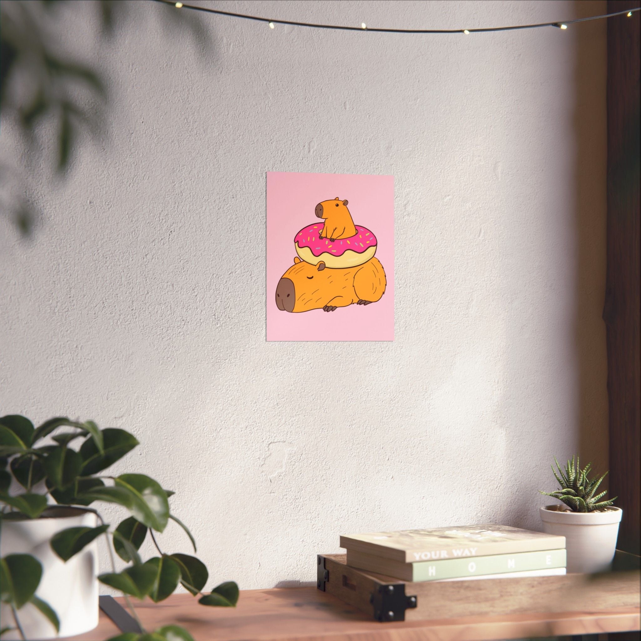 Capy Life wall art print featuring a cute capybara with a donut on a soft pink background, displayed in a nursery.