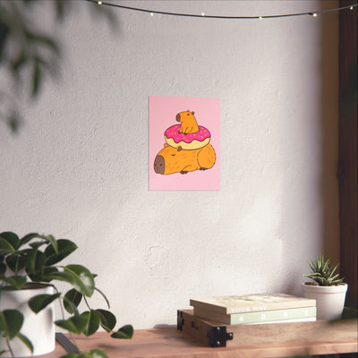 Capy Life wall art print featuring a cute capybara with a donut on a soft pink background, displayed in a nursery.