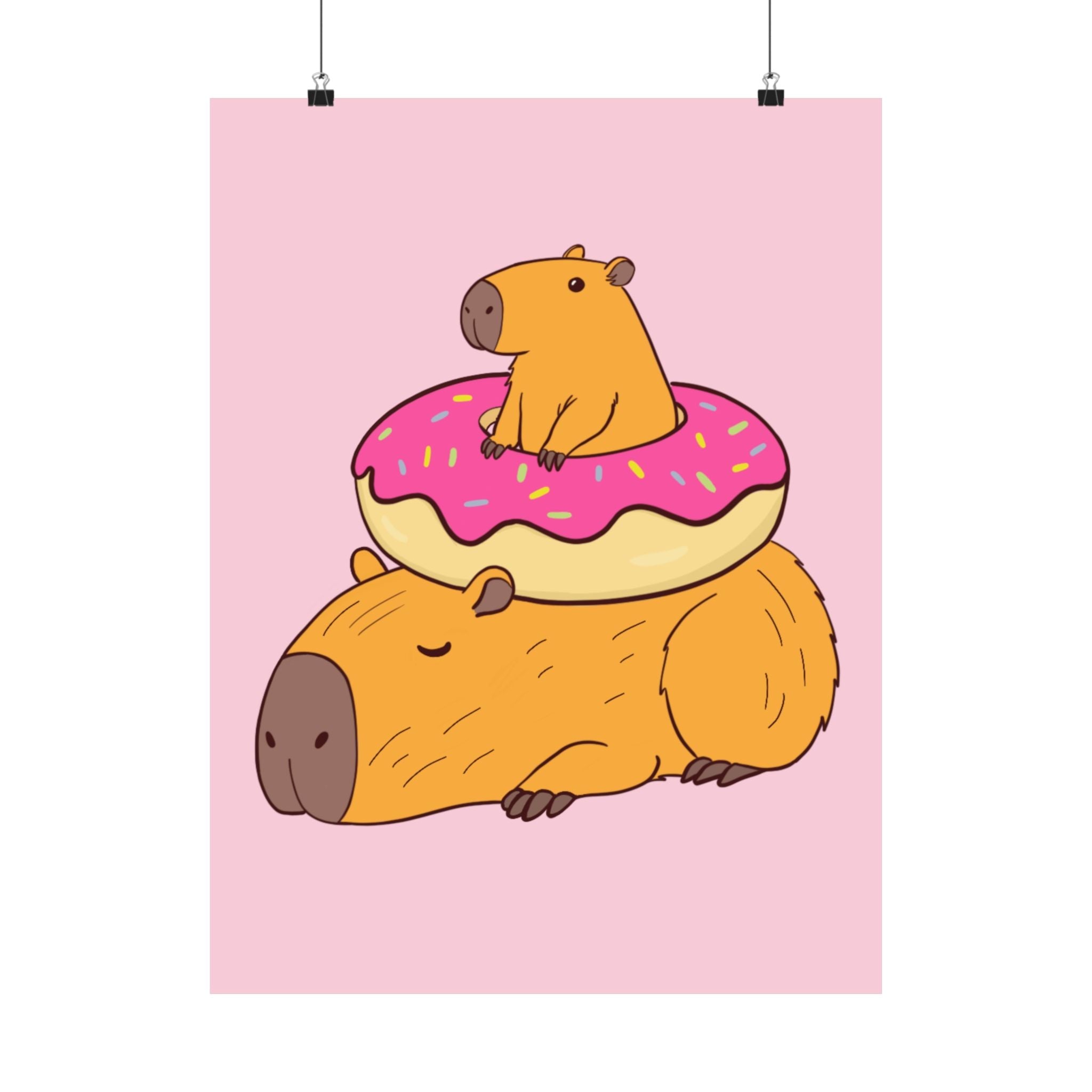 Capy Life wall art print featuring a cute capybara lounging under a frosted donut on a soft pink background.